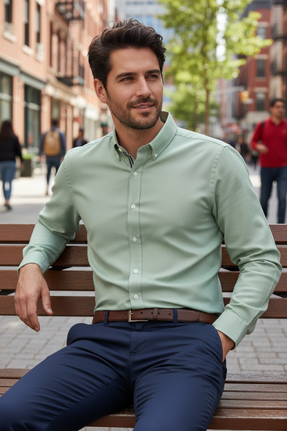 Modelo masculino sentado num banco com camisa verde sage